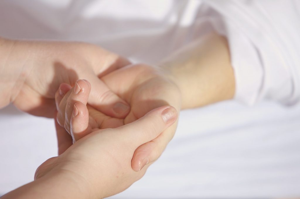 Ein Bild von zwei Händen, die eine Druckpunktmassage einer anderen Hand vornehmen.
